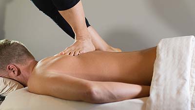 Ashiatsu Bar Massage, featuring skilled barefoot massage therapy with feet applying deep pressure on a client’s back.