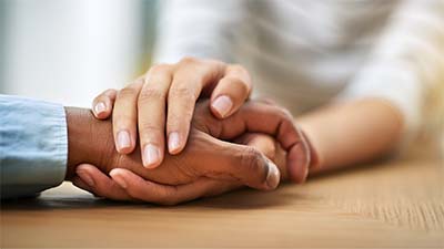 Two hands gently intertwined, symbolizing care, support, and healing through Oncology Massage.